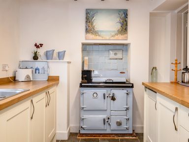 A kitchen with a vintage stove in a tiled alcove and wooden countertops at Honey Cottage in Port Isaac