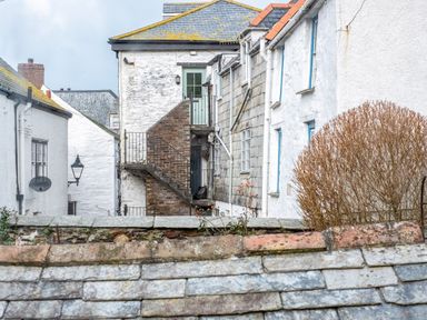 An outdoor view of white stone buildings with slate roofs and an external brick staircase in a village