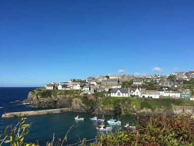 A coastal village with houses on cliffs and boats in the water at Honey Cottage in Port Isaac