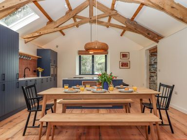 A kitchen and dining area with wooden beams plates with croissants and glasses of orange juice at 3 Caddaford Barns Buckfastleigh