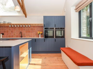 A kitchen with blue cabinets orange tiled backsplash black faucet and two ovens at 3 Caddaford Barns in Buckfastleigh