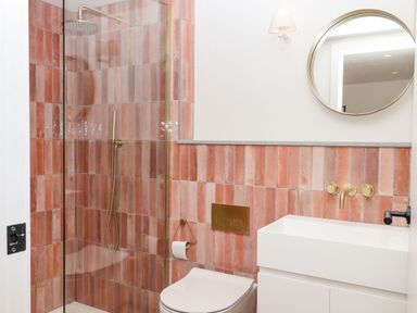 A bathroom with a glass shower enclosure white toilet and sink with terracotta tiles at 3 Caddaford Barns Buckfastleigh