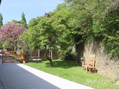 A garden with a wooden bench and table set a tree and a wooden gate at 3 Caddaford Barns in Buckfastleigh