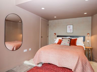 A bedroom with a bed, mirror, and nightstand at 3 Caddaford Barns, Buckfastleigh