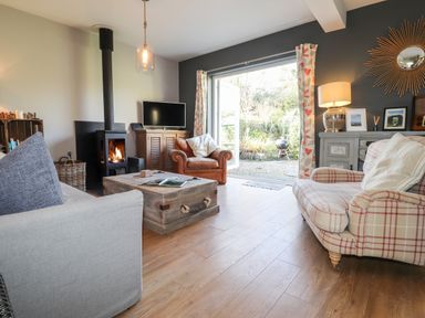 A living room with sofas a wood burning stove and a wooden coffee table at The Croft in Newport Pembrokeshire