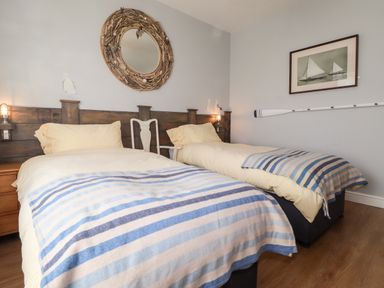 A bedroom with two single beds with striped blue blankets and wooden headboard at The Croft in Newport Pembrokeshire