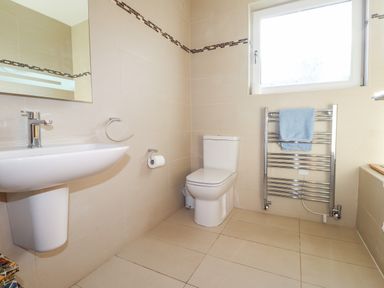 A bathroom with a white sink and toilet a towel on a heated rack and a window at The Croft in Newport Pembrokeshire