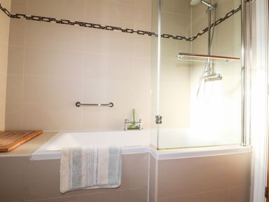 A bathroom with a bathtub shower enclosure and a towel hanging on the side at The Croft in Newport Pembrokeshire