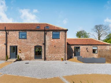 A brick house with three doors and three windows along with an outdoor seating area at Partridge Place in Burton Pidsea