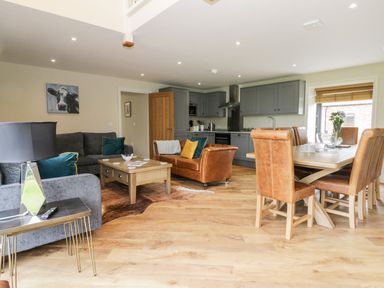 An open-plan living room and kitchen with sofas a coffee table and a dining table with chairs at Partridge Place in Burton Pidsea