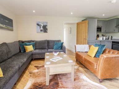 A living room with a gray sectional sofa a brown leather sofa a wooden coffee table and a cowhide rug at Partridge Place in Burton Pidsea