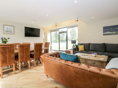 A living room with brown leather chairs a grey sofa a wooden coffee table and a dining table with chairs at Partridge Place in Burton Pidsea