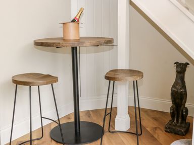 A corner with a round wooden table and two wooden stools with metal legs and a dog statue at Partridge Place Burton Pidsea