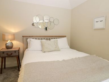 A bedroom with a double bed a bedside table with a lamp and circular mirrors on the wall at Partridge Place in Burton Pidsea