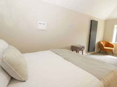 A bedroom with a bed a cushion a framed picture a radiator a small table and an armchair at Partridge Place in Burton Pidsea