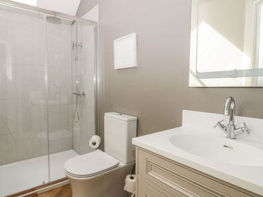 A bathroom with a shower enclosure a toilet and a sink with a faucet at Partridge Place in Burton Pidsea