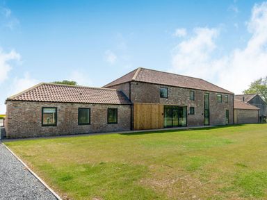 An exterior view of a two-story brick house with multiple windows and a tiled roof surrounded by a lawn at Partridge Place in Burton Pidsea