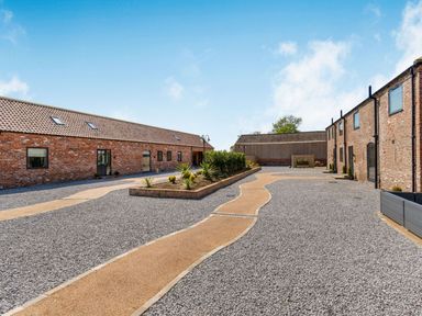 A courtyard with gravel ground and paved walking paths between two rows of brick buildings at Partridge Place in Burton Pidsea