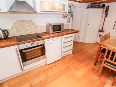 A kitchen with wooden countertop oven microwave dining table and chairs at Honeysuckle Cottage in St Agnes