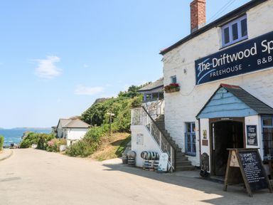 A street view with a pub named The Driftwood Spars and sea in the background at Honeysuckle Cottage in St Agnes