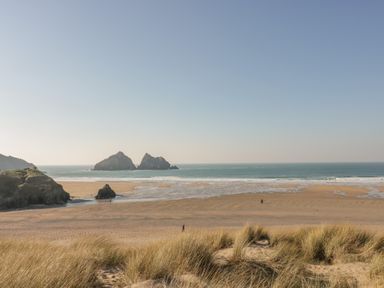 A beach with sand dunes and rocks in the ocean at Palm View in Holywell Bay