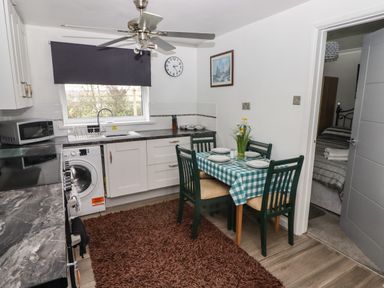 A kitchen with a dining table set for four and a washing machine visible at 13 Gower Holiday Village in Scurlage