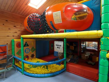An indoor toddler play area with a ball pit slide and soft play toys at 13 Gower Holiday Village in Scurlage