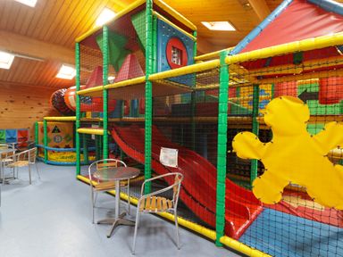 An indoor children's play area with climbing frames slides and small tables and chairs at 13 Gower Holiday Village in Scurlage