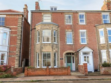 A brick residential building with multiple windows and a green front door at Collett House in Southwold