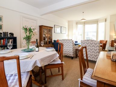 A combined dining and living room with a set table and patterned armchairs at Collett House in Southwold