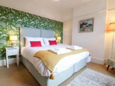 A bedroom with a double bed and green patterned wallpaper at Collett House in Southwold