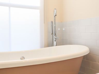 A bathroom with a freestanding bathtub and a silver faucet near a window at Collett House in Southwold
