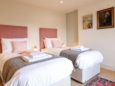 A bedroom with two single beds each with white bedding and folded towels at Collett House in Southwold