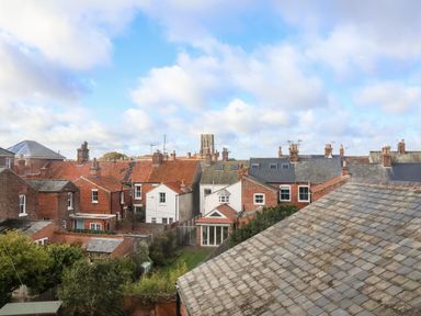 A view of the backyards and rooftops of brick houses under a blue sky with clouds at Collett House in Southwold
