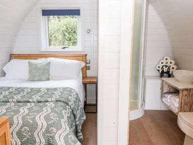 A bedroom with a bed and side table next to a bathroom with toilet and sink at Ash Saltash