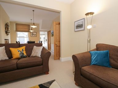 A living room with two brown sofas with cushions and a floor lamp at Derwent Cottage in Keswick