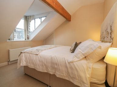A bedroom with a bed under a sloped ceiling window and a wooden beam at Derwent Cottage in Keswick