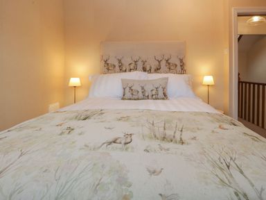 A bedroom with a bed featuring animal patterned bedding and two bedside lamps at Derwent Cottage in Keswick