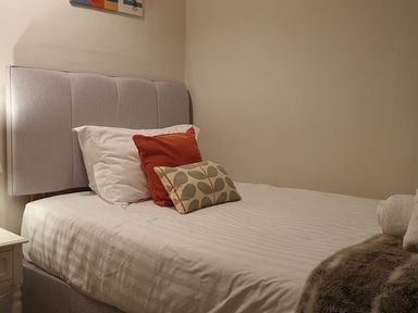 A bedroom with a bed with white sheets and three pillows a red one white one and a patterned one at Derwent Cottage Keswick