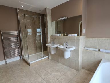A bathroom with dual washbasins and a shower at Derwent Cottage in Keswick