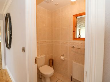 A small bathroom with a toilet a toilet paper holder a window with a wooden frame and a radiator at Hazelwood in Leap County Cork