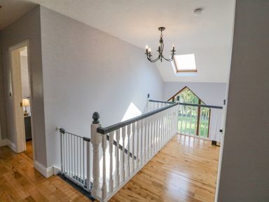 A landing with wooden floor white and dark railing and a chandelier at Hazelwood in Leap County Cork