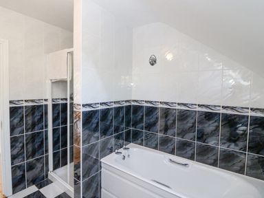 A bathroom with a bathtub and a shower area with tiled walls at Hazelwood in Leap County Cork