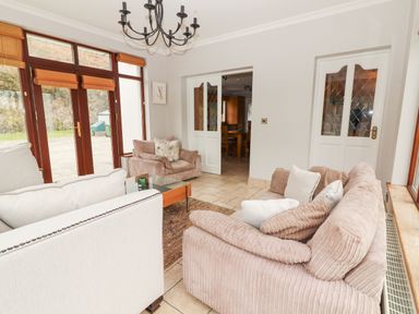 A living room with beige sofas a coffee table and glass doors leading outside at Hazelwood in Leap County Cork