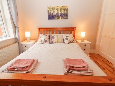A bedroom with a wooden bed frame white bedding two bedside tables with lamps and folded towels at Hazelwood in Leap County Cork