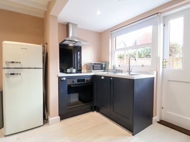 A kitchen with a refrigerator oven microwave sink and a door with window at Poppy Cottage in Southwold