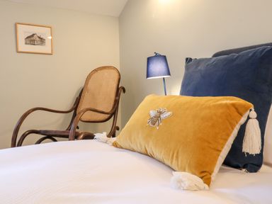 A bedroom with a bed with two pillows a wooden chair a blue lamp and a framed picture on the wall at Poppy Cottage in Southwold