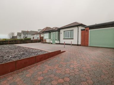 Exterior view of a one-story house with a tiled roof green door and garage with patterned driveway Bamburgh Dunes Bamburgh near Seahouses
