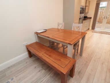 A wooden dining table with two chairs and a bench in a kitchen area at Bamburgh Dunes Bamburgh near Seahouses