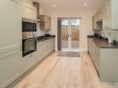 A kitchen with wooden floor cabinets double glass door and built in oven at Bamburgh Dunes Bamburgh near Seahouses